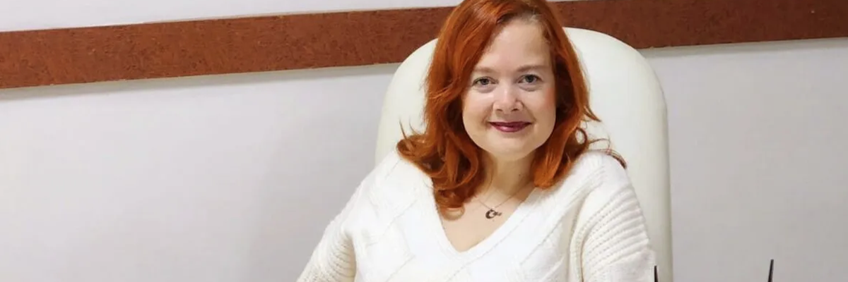 Resim: Fotoğrafta, Psk. İlknur Peder orta uzunlukta kızıl saçlarıyla, beyaz örgü bir kazak giyerek sandalyede oturuyor. Arka plan sade ve profesyonel; beyaz duvar üzerinde yatay kahverengi bir şerit bulunuyor. Yüz ifadesi sakin, güven veren bir terapist duruşu taşıyor.